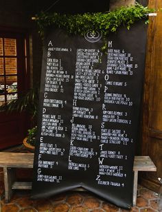 a black menu board sitting on top of a stone floor next to a wooden bench