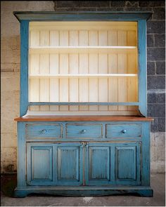 an old blue china cabinet with wooden shelves