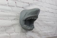 a fake shark head mounted to the side of a brick wall with it's mouth open