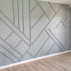 an empty room with wood flooring and grey painted wallpaper on the side of it