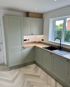 an empty kitchen with wooden floors and green cupboards, white walls and wood flooring