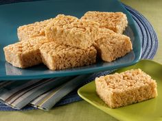 several pieces of rice krispy treats on a blue plate next to a green plate