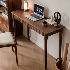 a laptop computer sitting on top of a wooden desk next to a vase and lamp