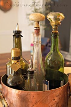 several bottles are in an old copper bucket