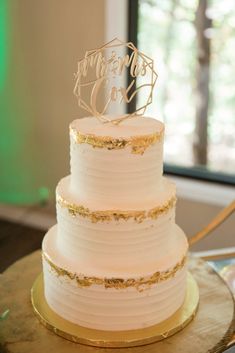 a three tiered white cake with gold accents