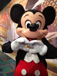 the mickey mouse mascot is standing in front of a wall