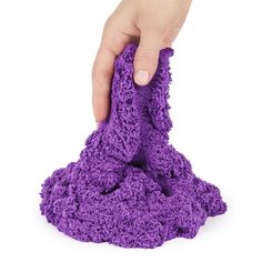 a hand holding a purple cloth on top of a white surface