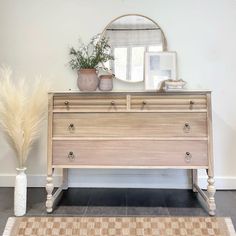 a dresser with two vases and a mirror on top of it next to a rug