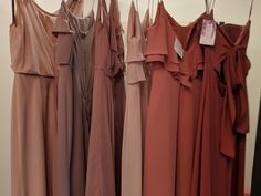 there are many different colored dresses hanging on the clothes rack in front of each other