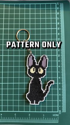 a cross stitch keychain with the words pattern only on it and a black cat