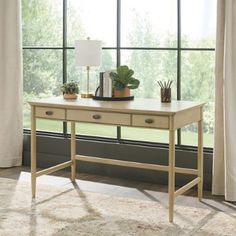 a desk with two drawers in front of a window and a potted plant on top