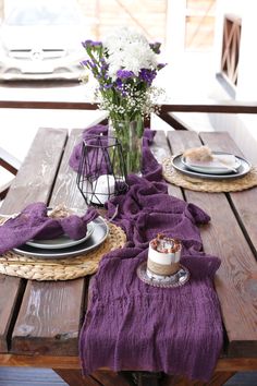 the table is set with purple linens and place settings