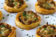 small pastries with various toppings on a white plate and garnished with parsley