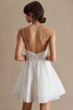 a woman in a short white dress looking back