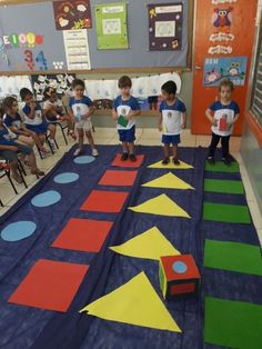 several children standing in front of an area made out of foam blocks and colored shapes