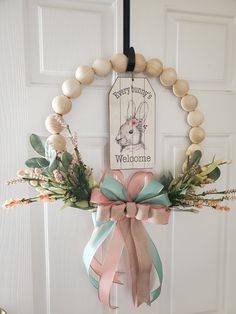 a door hanger with a wreath and ribbon hanging on it's front door