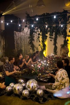 a group of people sitting around a table with disco balls and candles on top of it