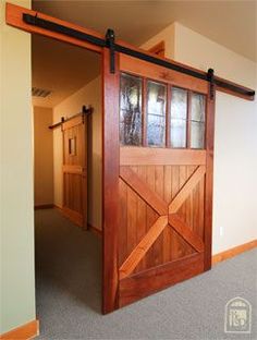 an open wooden door in the middle of a room with carpeted flooring and white walls