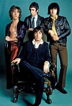 the rolling stones are posing for a portrait in their suits and ties, one man is sitting on a chair