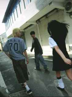 three people walking down the street in front of a building