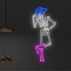 a neon skeleton with a hat is standing on a stool in front of a black wall