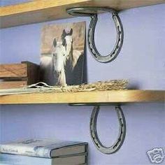 two wooden shelves with horse heads and horseshoes hanging from the top, along with books on each shelf