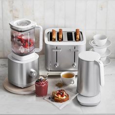 a toaster, coffee maker, and cups on a counter with food in them