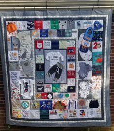 a quilt hanging on the side of a brick wall covered in patches and stickers