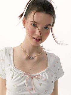 a young woman wearing a white shirt and pink ribbon around her neck