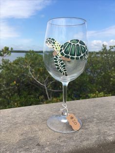 a wine glass with a sea turtle painted on the side and a tag attached to it