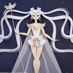 an origami paper doll with white hair holding a wand and wearing a tiara