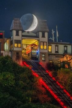 a building with stairs leading up to it and the moon in the sky behind it