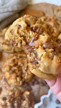 a person holding up a chocolate chip cookie