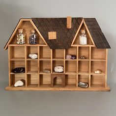 a doll house made out of wood with lots of bottles and rocks on the outside