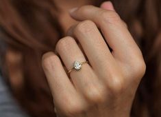 a close up of a person wearing a ring with a heart shaped diamond on it