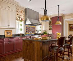 a large kitchen with wooden floors and red painted cabinets, along with an island in the middle