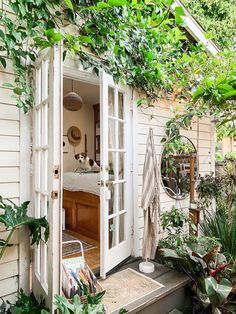 an open door leading into a room with plants growing on the outside wall and inside