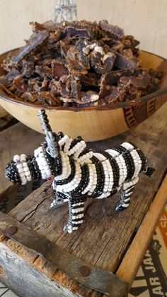 a zebra figurine sitting on top of a wooden table next to a bowl of food