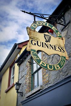 the guinness pub sign is hanging from the side of the building