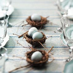 four eggs in a nest sitting on top of a blue and white table cloth next to silverware