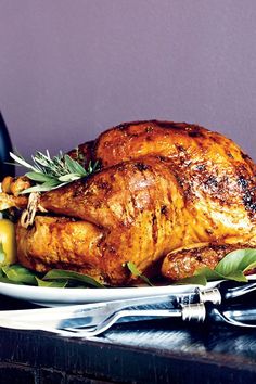 a roasted turkey on a plate with garnishes and wine bottle in the background