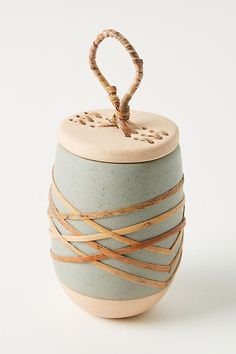 a ceramic container with rope wrapped around the top and bottom, sitting on a white surface