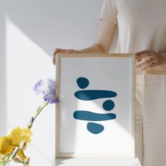 a woman holding up a framed art print with the word love in blue on it