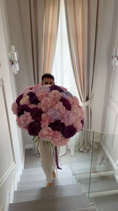 a man holding a large bouquet of flowers in front of his face on the stairs