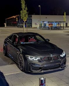 a black car parked on the side of a road at night with people standing around