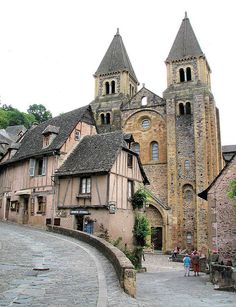 an old building with two towers and people walking on the sidewalk