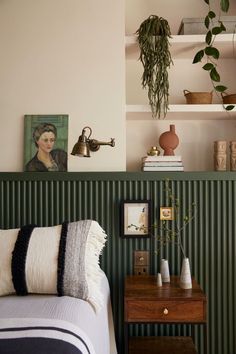 a bedroom with green and white striped wallpaper, potted plants and a bed