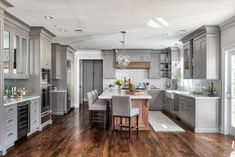 a large kitchen with wooden floors and gray cabinets, along with an island in the middle