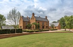 a large brick house sitting on top of a lush green field