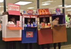 three people standing in front of mcdonald's drive thru booths made out of cardboard boxes